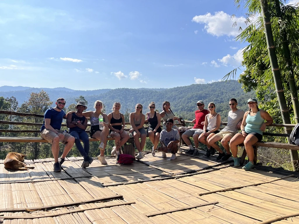Guests on a bamboo deck looking out over the hills from the village