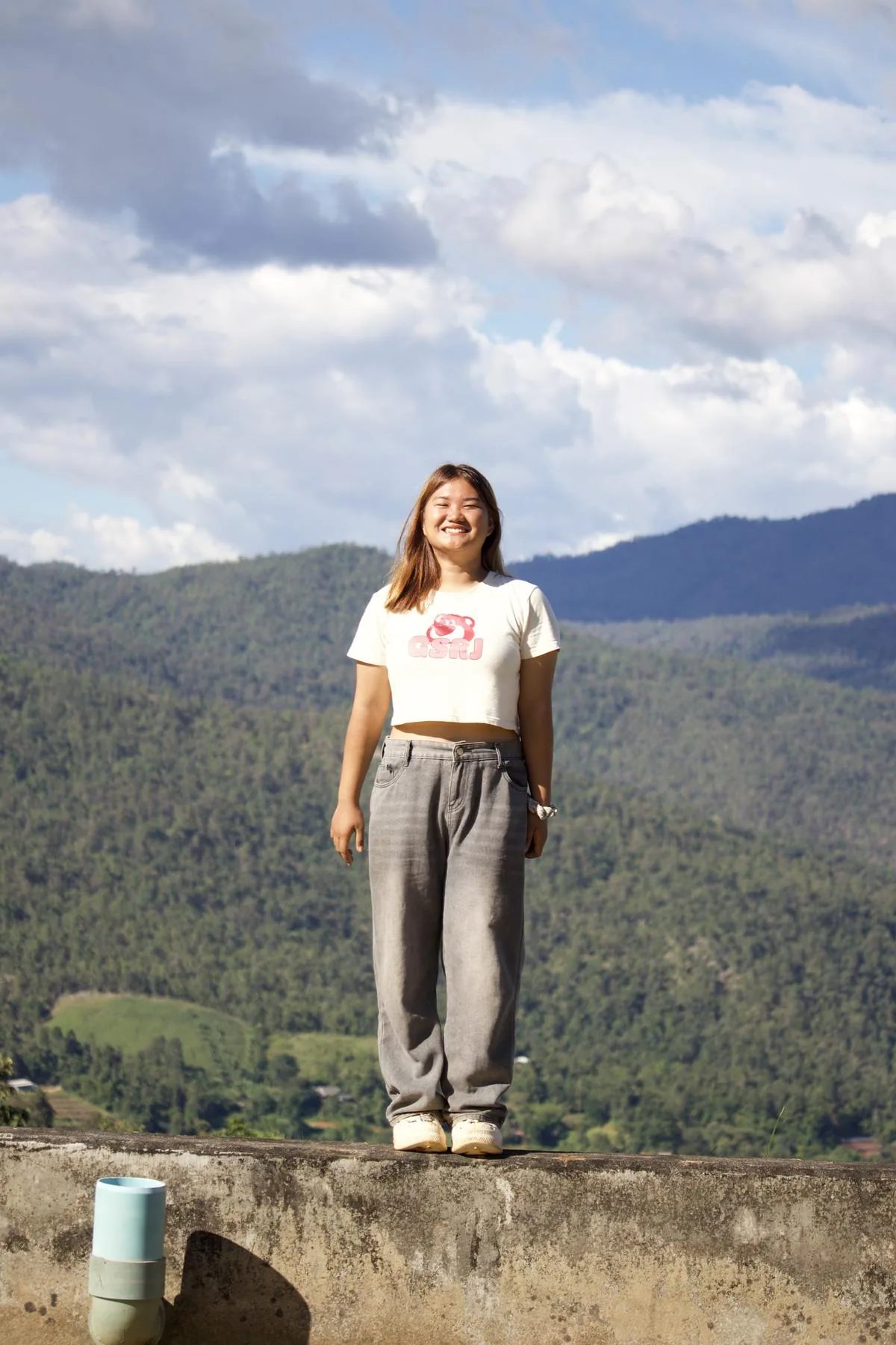 A woman smiling at a mountain viewpoint above the valley
