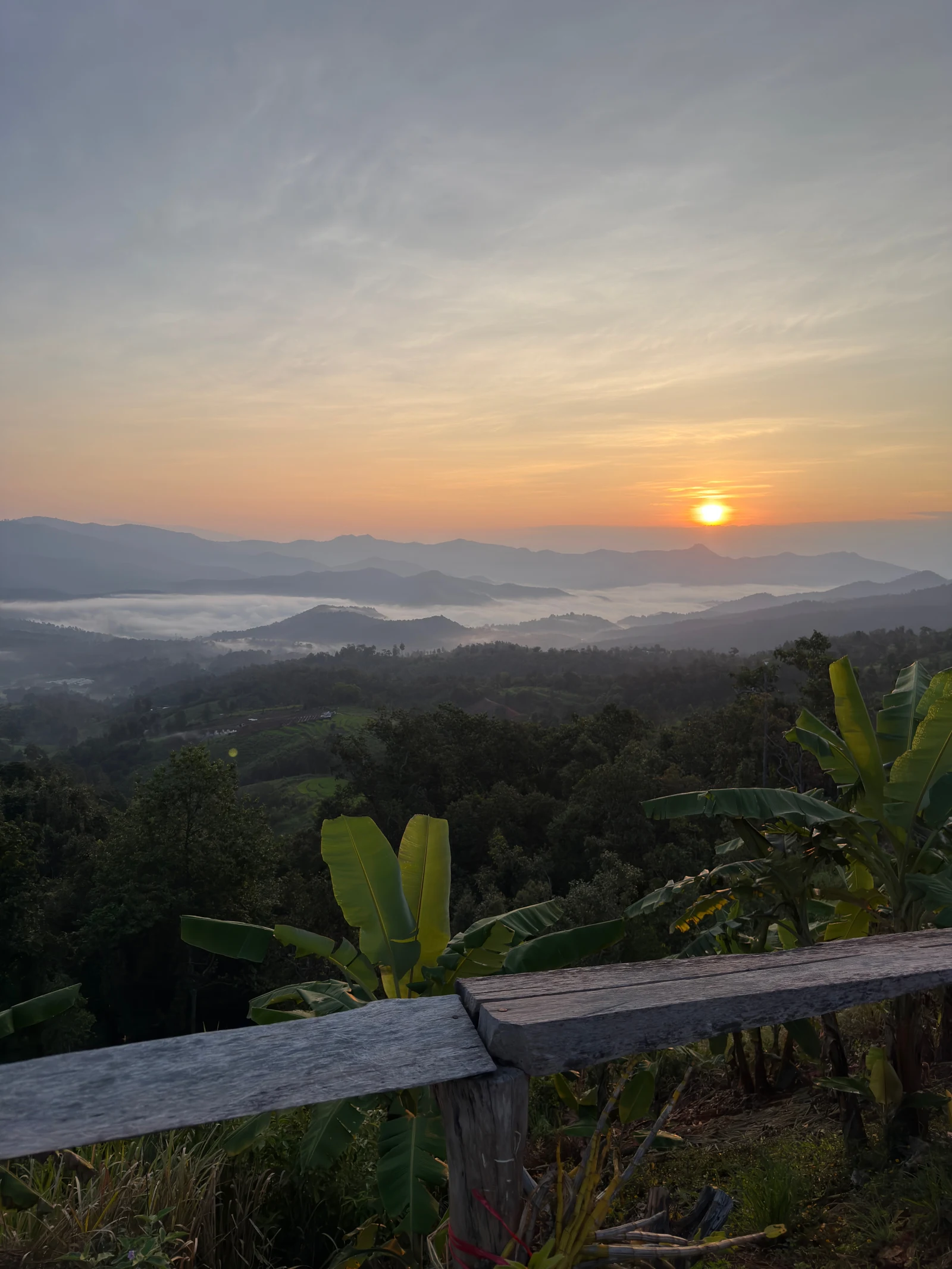 Sunrise glowing over layered mountains beyond the village